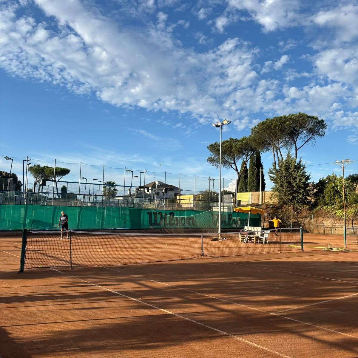 Una partita sulla terra battuta sotto il cielo di Roma, con i pini sullo sfondo